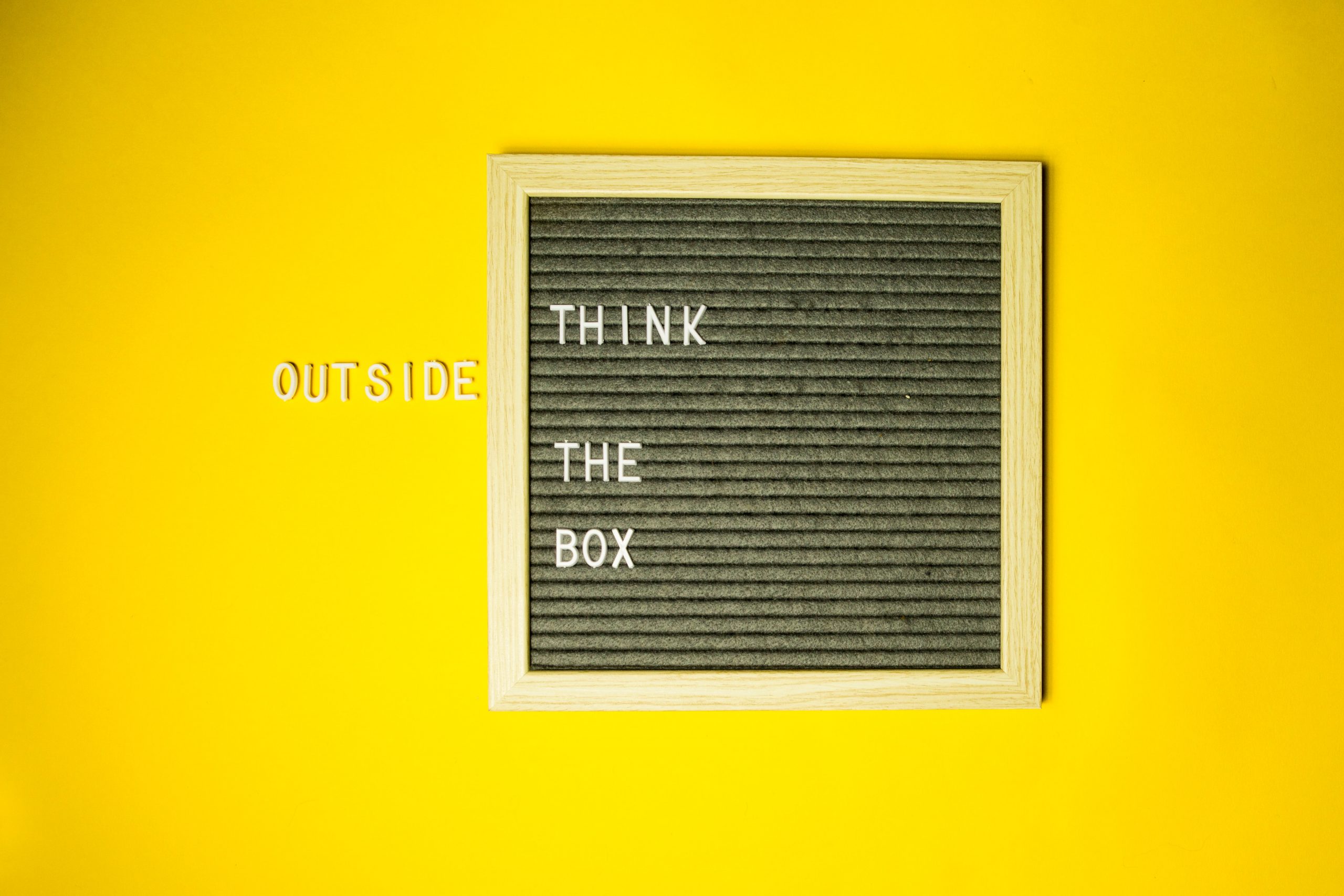 Bilderrahmen mit dem Spruch "Think Outside The Box". Das Wort Outside steht außerhalb des Rahmens.